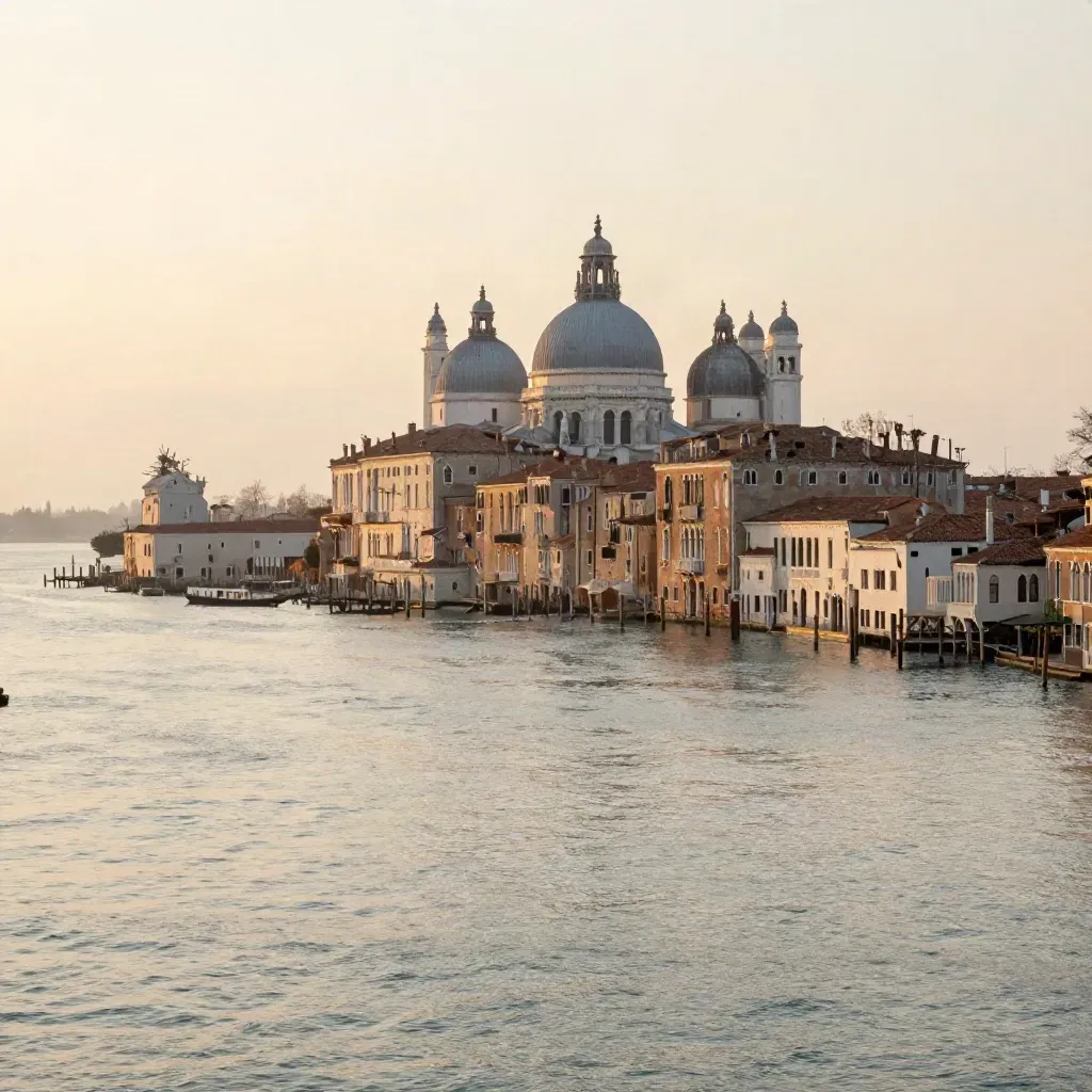 Venezia all’alba con la laguna calma e i campanili illuminati dalla luce dorata.